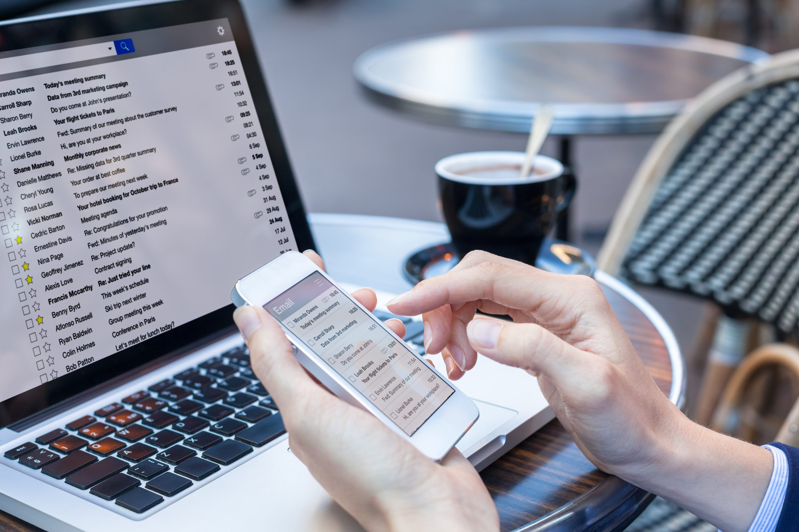 Person reading emails on smartphone and laptop