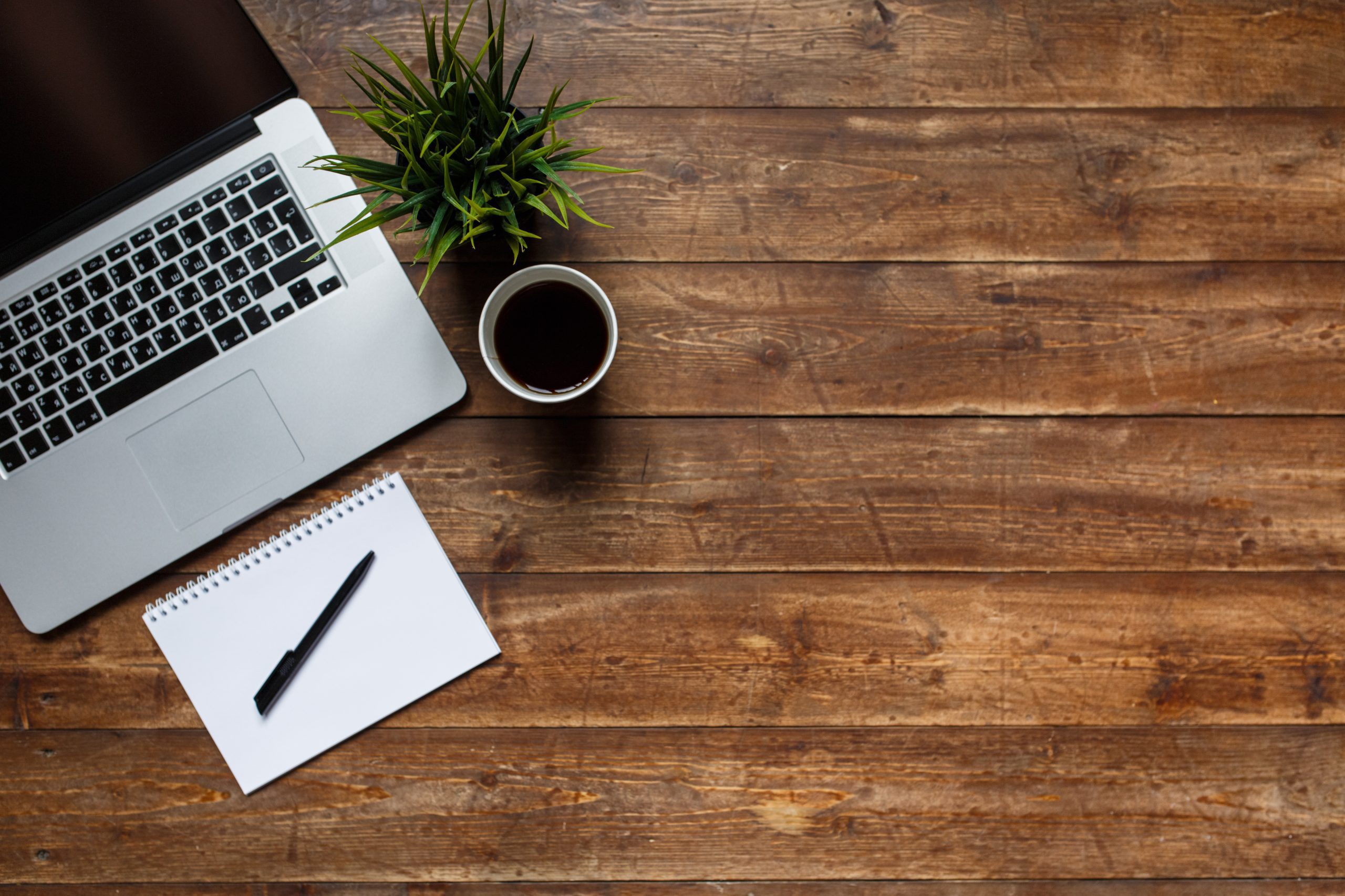 Desk with a laptop, notebook, and coffee cup