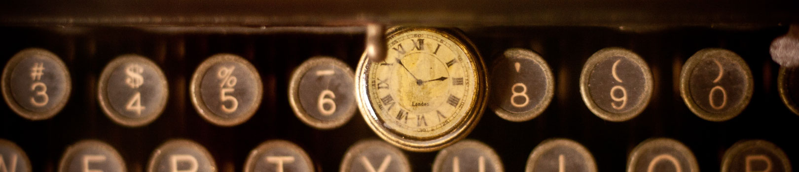 pocket watch on top of an old typewriter